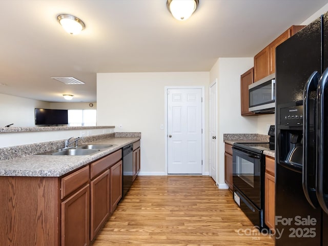 kitchen with sink, light hardwood / wood-style flooring, kitchen peninsula, and black appliances