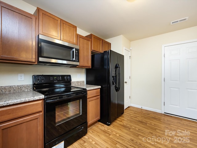 kitchen with light hardwood / wood-style flooring and black appliances