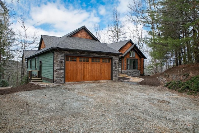 rustic home featuring stone siding, roof with shingles, driveway, and an attached garage