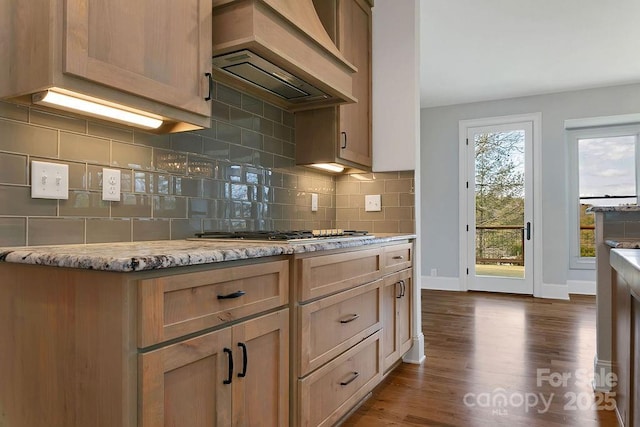 kitchen featuring custom exhaust hood, light brown cabinets, dark hardwood / wood-style flooring, stainless steel gas stovetop, and decorative backsplash