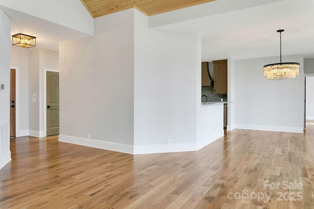 empty room with an inviting chandelier, light hardwood / wood-style floors, and wooden ceiling