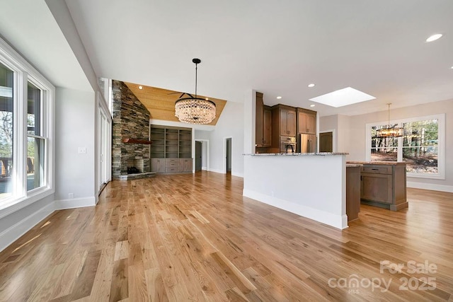 unfurnished living room with a notable chandelier, light hardwood / wood-style flooring, and a fireplace