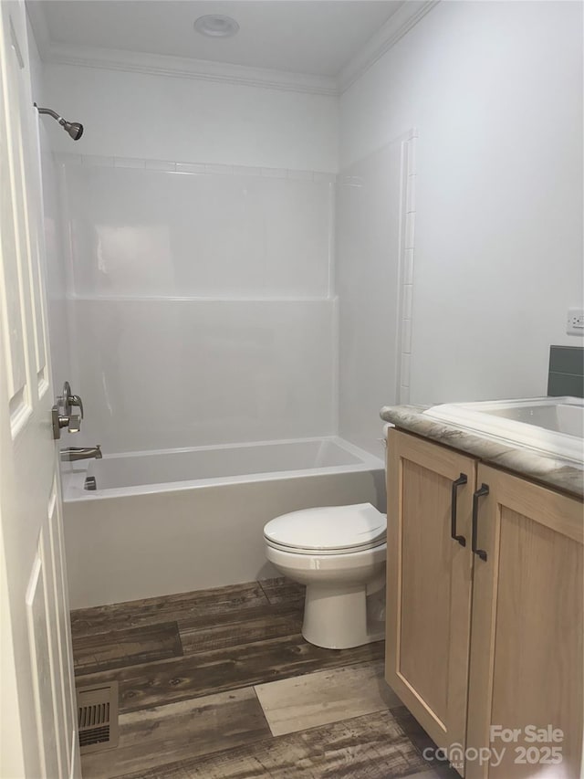 full bathroom featuring wood-type flooring, ornamental molding, vanity, toilet, and tub / shower combination