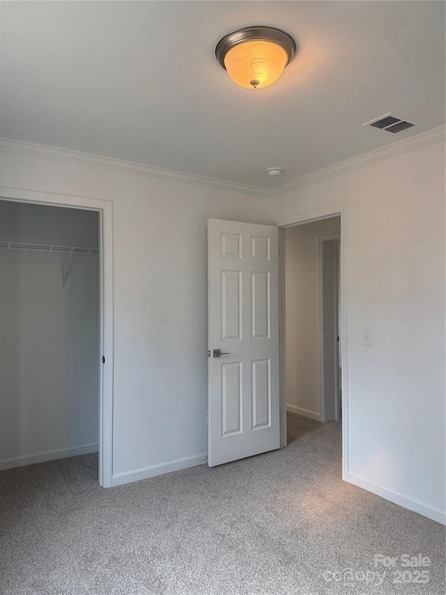 unfurnished bedroom with carpet floors, ornamental molding, and a closet