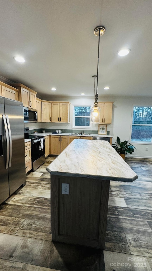 kitchen with light brown cabinetry, decorative light fixtures, a kitchen island, and appliances with stainless steel finishes