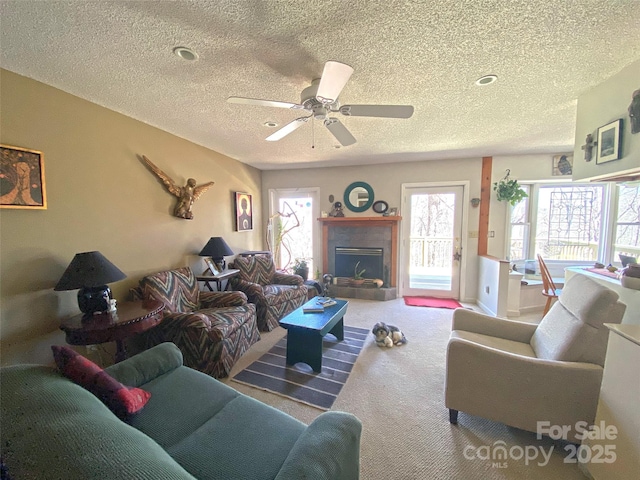 living room featuring a textured ceiling, carpet, a fireplace, and a ceiling fan