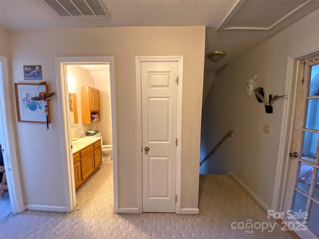 hall with baseboards, visible vents, light colored carpet, and an upstairs landing