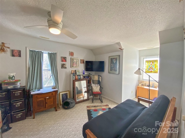 bedroom featuring baseboards, visible vents, a ceiling fan, light colored carpet, and a textured ceiling