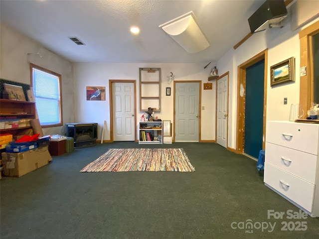 misc room featuring visible vents, dark carpet, and baseboards