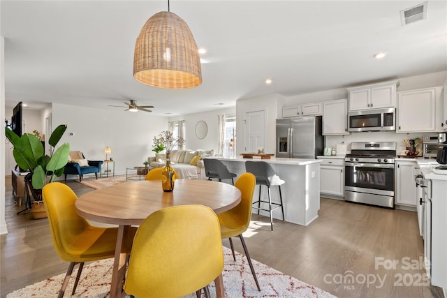 dining space with ceiling fan and wood-type flooring