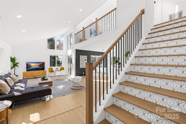 stairs with hardwood / wood-style flooring and a high ceiling