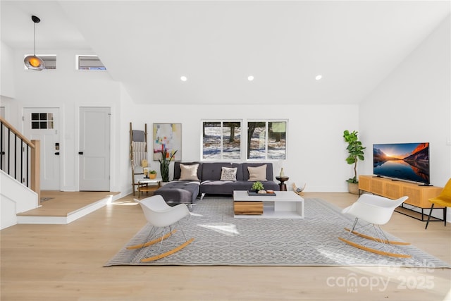 living room with a towering ceiling and light hardwood / wood-style floors