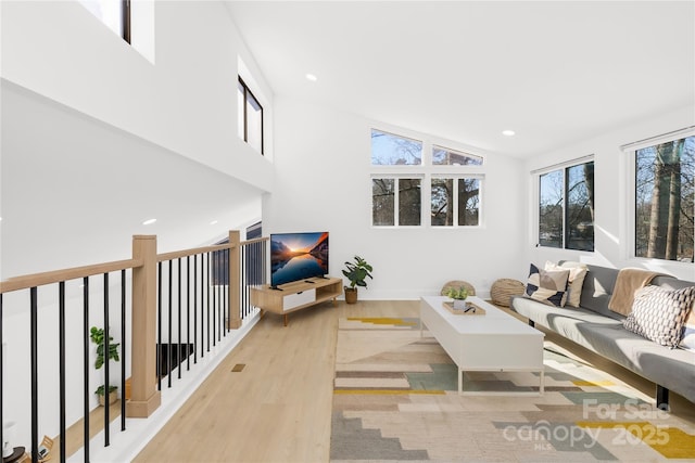 living room with high vaulted ceiling and light wood-type flooring