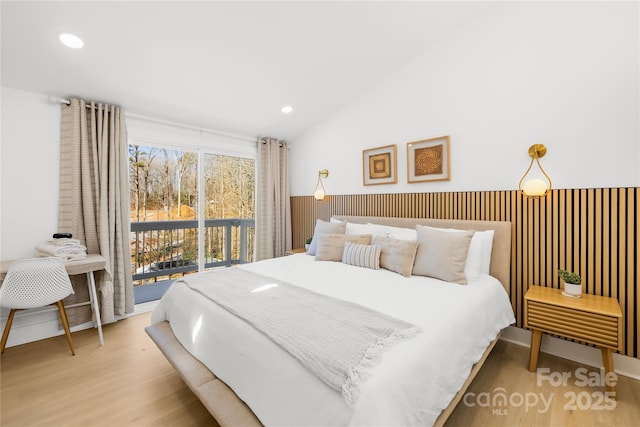 bedroom featuring access to exterior, vaulted ceiling, and light hardwood / wood-style flooring