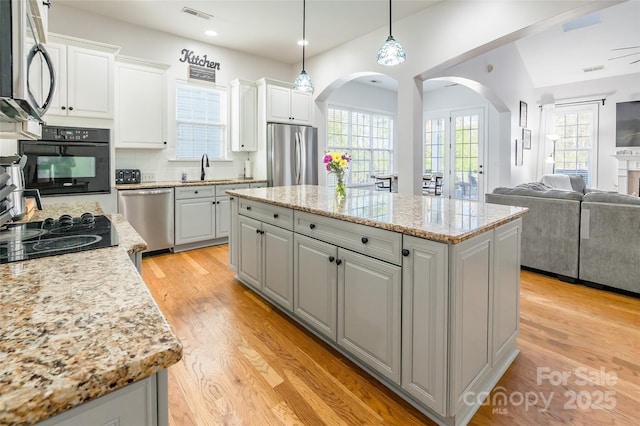 kitchen with a kitchen island, white cabinetry, decorative backsplash, hanging light fixtures, and black appliances