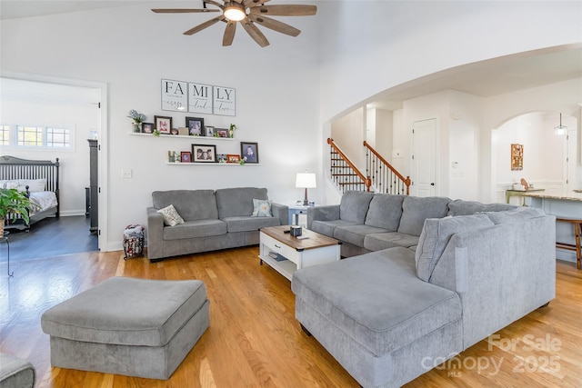 living room with ceiling fan, vaulted ceiling, and light wood-type flooring