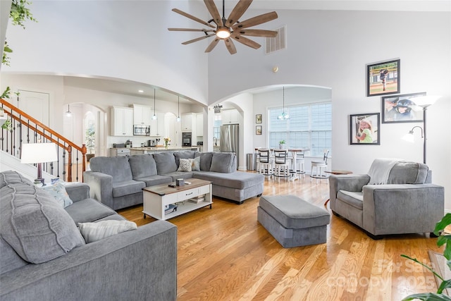 living room featuring a high ceiling, ceiling fan, a wealth of natural light, and light wood-type flooring