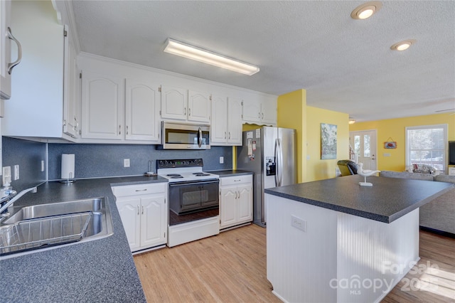 kitchen with sink, light hardwood / wood-style flooring, appliances with stainless steel finishes, backsplash, and white cabinets