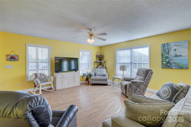 living room with ceiling fan, light hardwood / wood-style floors, a textured ceiling, and a wealth of natural light