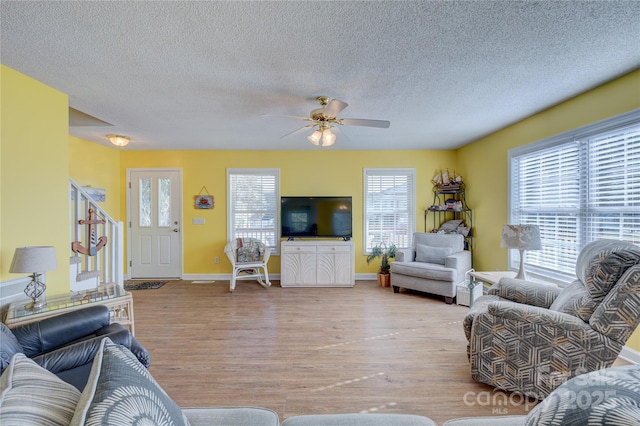 living room featuring ceiling fan, a wealth of natural light, a textured ceiling, and light wood-type flooring