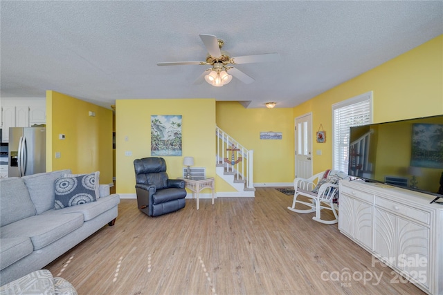 living room featuring ceiling fan, a textured ceiling, and light hardwood / wood-style floors