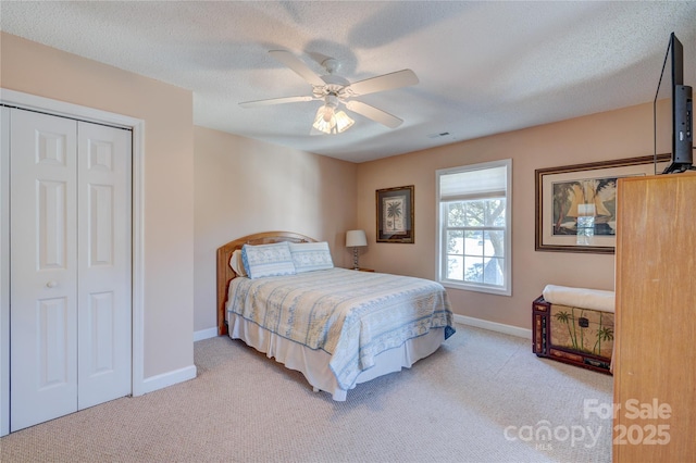 carpeted bedroom featuring a textured ceiling, a closet, and ceiling fan