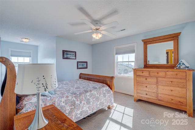 bedroom featuring multiple windows, light colored carpet, and ceiling fan