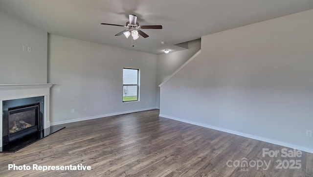 unfurnished living room featuring dark wood-type flooring and ceiling fan