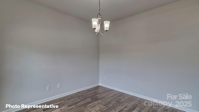 empty room with dark hardwood / wood-style flooring and a notable chandelier