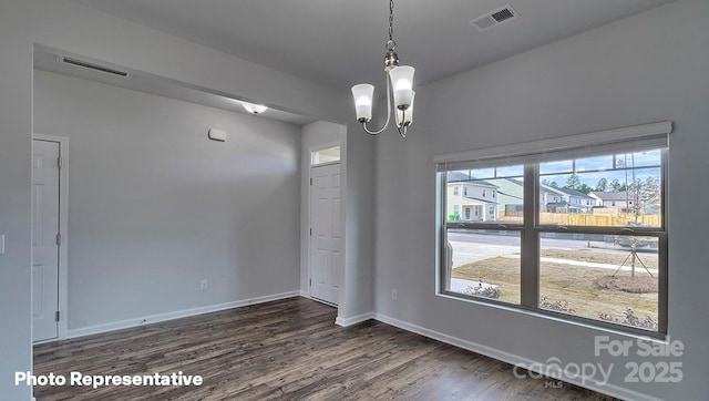 spare room with a notable chandelier, dark hardwood / wood-style floors, and a healthy amount of sunlight