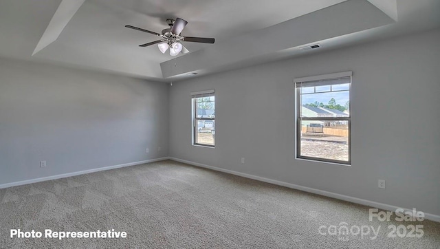 carpeted empty room with ceiling fan and a tray ceiling