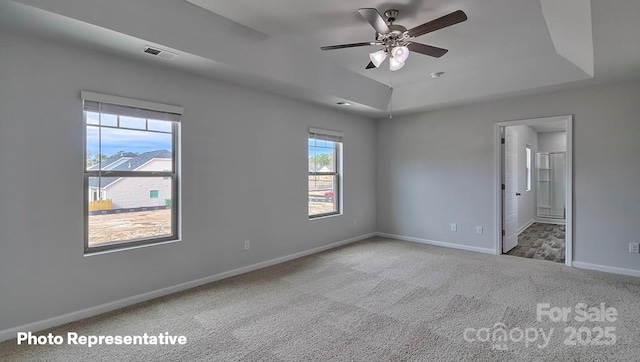 carpeted spare room featuring a raised ceiling and ceiling fan