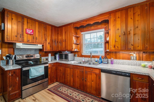 kitchen featuring stainless steel appliances, sink, a textured ceiling, and light hardwood / wood-style floors