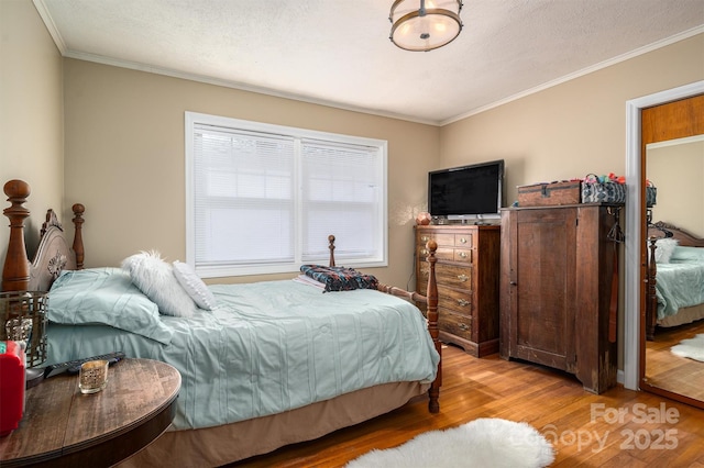 bedroom featuring ornamental molding, a textured ceiling, and light hardwood / wood-style flooring