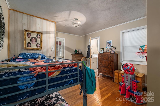 bedroom featuring crown molding, hardwood / wood-style floors, ensuite bathroom, and a textured ceiling