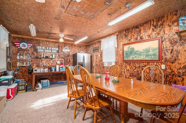 dining room with ceiling fan, carpet, and wood walls