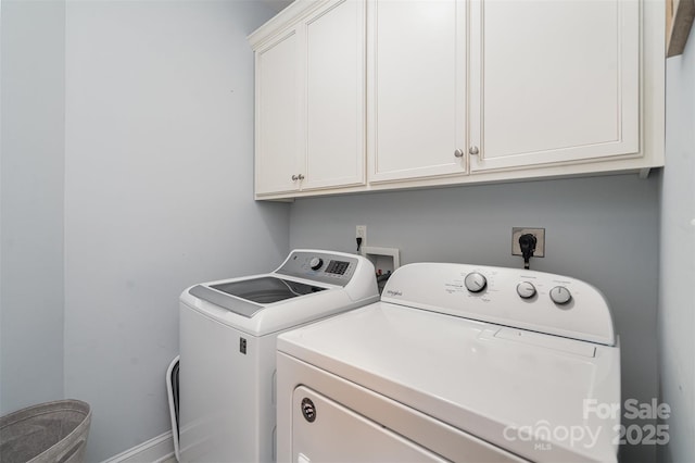 clothes washing area featuring cabinets and separate washer and dryer