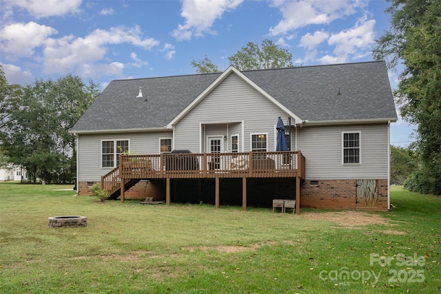 rear view of house featuring a wooden deck, a fire pit, and a lawn