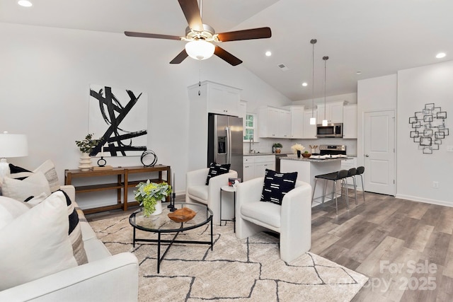 living room featuring ceiling fan, lofted ceiling, and light hardwood / wood-style floors