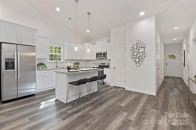 kitchen featuring a breakfast bar area, a kitchen island, pendant lighting, stainless steel appliances, and white cabinets