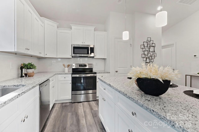 kitchen with decorative light fixtures, light hardwood / wood-style flooring, stainless steel appliances, and white cabinets