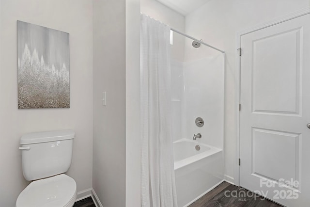 bathroom featuring wood-type flooring, tub / shower combination, and toilet