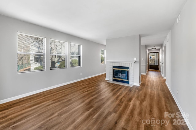 unfurnished living room with a brick fireplace and dark wood-type flooring