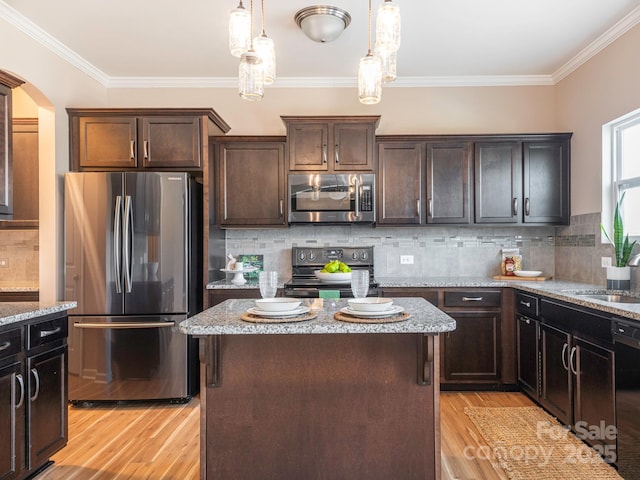 kitchen with backsplash, light stone countertops, a center island, and appliances with stainless steel finishes