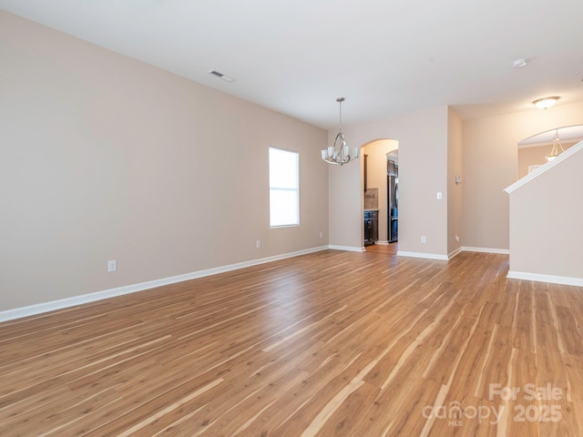 unfurnished living room with an inviting chandelier and light wood-type flooring