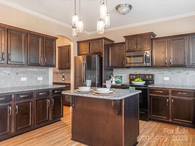 kitchen featuring pendant lighting, appliances with stainless steel finishes, a center island, ornamental molding, and decorative backsplash