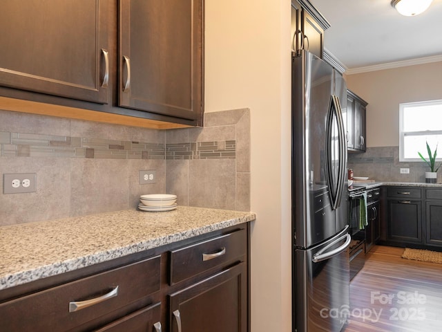 kitchen with stainless steel fridge, tasteful backsplash, dark brown cabinetry, light stone countertops, and ornamental molding