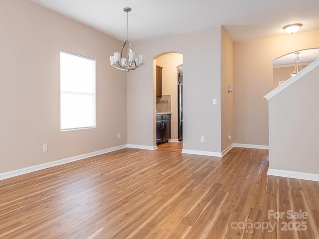 unfurnished living room featuring a chandelier and light hardwood / wood-style flooring