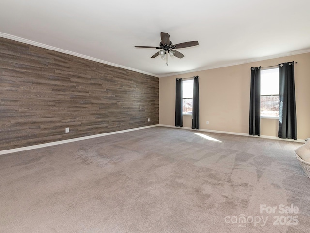 carpeted spare room featuring ornamental molding, ceiling fan, and wood walls