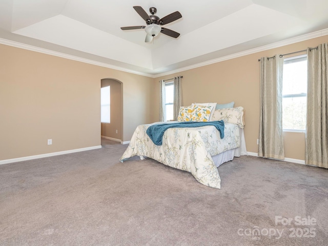 carpeted bedroom with crown molding, ceiling fan, and a tray ceiling